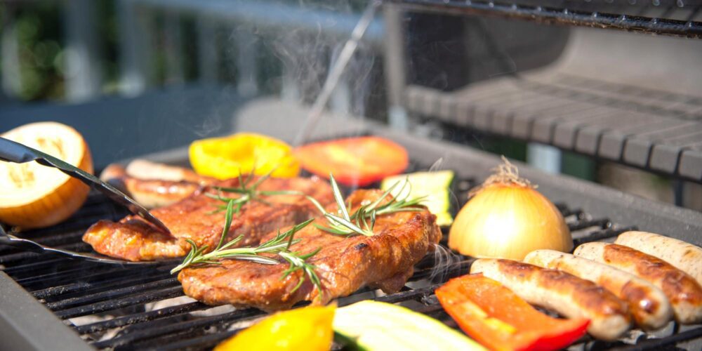 Closeup of someone grilling meat and vegetables. Outdoor grills are available at The Arno.
