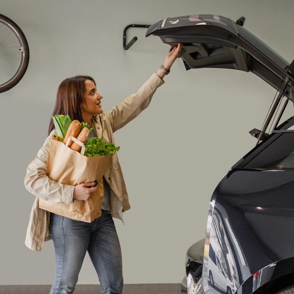Woman unloading groceries from the trunk of her car in a private garage, included in each unit at The Arno.